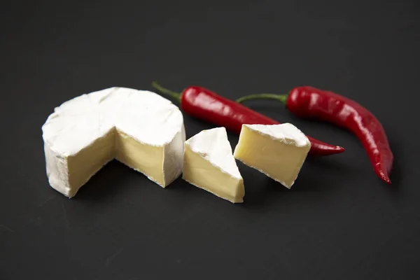 Sýr camembert nebo brie s chilli papričkou na tmavém pozadí. Boční pohled. — Stock fotografie