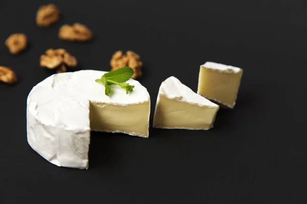 Sýr camembert nebo brie s vlašským ořechem na tmavém pozadí. Boční pohled. — Stock fotografie