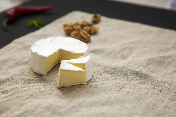 Bílý sýr camembert nebo brie a řezy s ořechy a chilli papričky. Produkce mléka. Boční pohled. — Stock fotografie