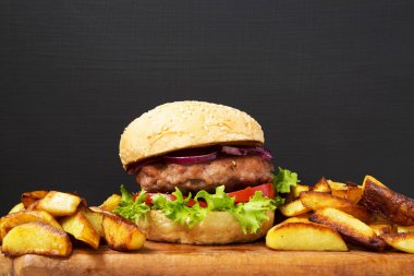 Ahşap tahta üzerinde kızarmış patates ile taze Amerikan burger. Kapat