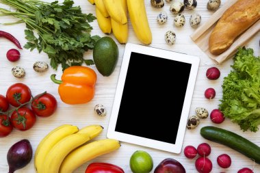 Tablet ile ham sağlıklı yiyeceklerin ortasında beyaz bir ahşap arka plan üzerinde ayarlayın. Düz yatıyordu. Üstten Görünüm. Yukarıdan.