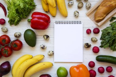 Sağlıklı gıda kavramı. Beyaz ahşap zemin üzerinde defter ile çiğ sağlıklı gıda bileşimi. Düz yatıyordu. Üstten Görünüm. Yukarıdan.