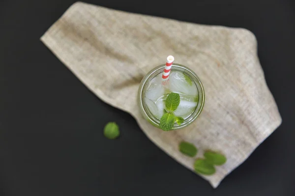 Bicchiere di mojito con calce, ghiaccio e menta su fondo scuro. Vista dall'alto. Posa piatta — Foto Stock