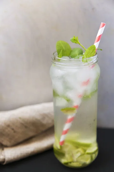 Summer drink with ice, fresh lime and mint on dark background. Side view. — Stock Photo, Image