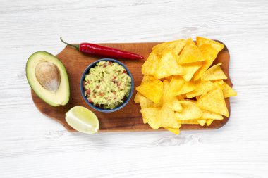 Geleneksel Meksika guacamole kase ve malzemelerle ahşap tahta üzerinde Nacho. Beyaz ahşap arka plan. Üstten Görünüm. 