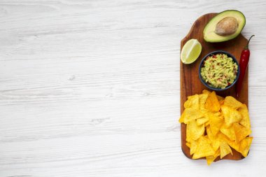 Geleneksel Meksika guacamole kase ve malzemelerle ahşap tahta üzerinde Nacho. Beyaz ahşap arka plan. Üstten Görünüm. Kopya alanı.