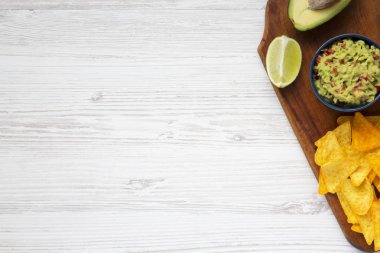 Guacamole Mısır Nacho, kireç, kesme yarı ahşap beyaz arka plan üzerinde avokado. Üstten Görünüm. Kopya alanı.