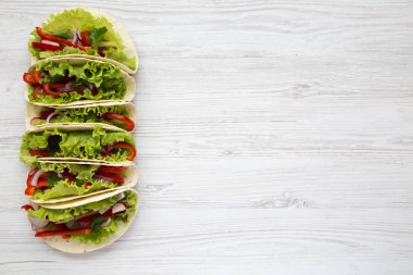 Vejetaryen tacos marul, biber, soğan ve domates Beyaz ahşap zemin üzerinde yapılmış. Yukarıdan. Üstten Görünüm