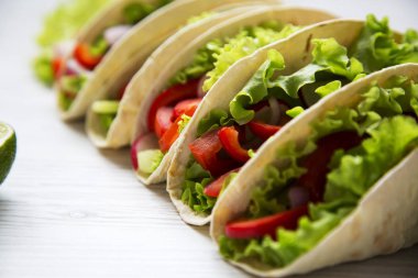 Beyaz ahşap zemin üzerinde taze vejetaryen yemek. Portre.