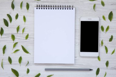 Yaratıcı masaüstü smartphone, not defteri ve kalem ile. Üstten Görünüm. Düz yatıyordu.