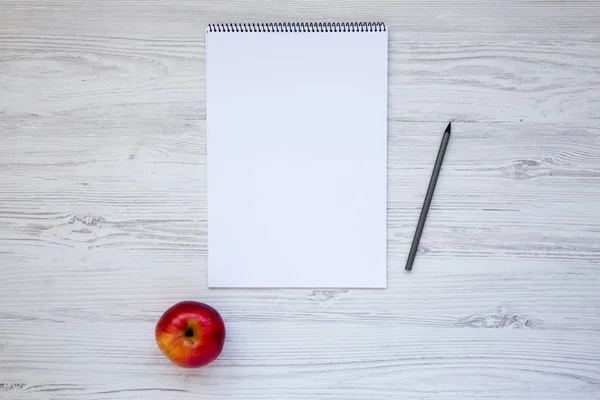 Lugar de trabajo con cuaderno, lápiz y manzana. Composición mínima. Vista superior . — Foto de Stock