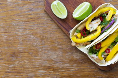 Tacos ile ızgara tavuk fileto, taze sebze, kireç ahşap tahta üzerinde. En iyi manzara, yukarıda. Kopya alanı.