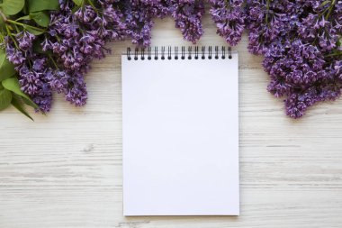 Beyaz ahşap zemin üzerinde defter ile Lila çiçek bir buket. Uzay kopyalayın. Anneler günü. Üstten Görünüm.