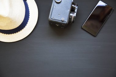 Vintage fotoğraf makinesi, şapka ve siyah arka plan üzerine smartphone. Üstten Görünüm. Kopya alanı.