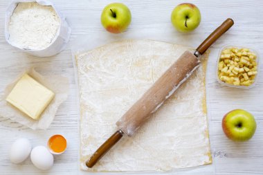 Beyaz ahşap zemin, üstten görünüm üzerine elmalı turta malzemeler. Düz yatıyordu.