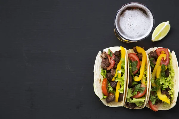 Кукурузные лепешки с говядиной и овощами, пиво и лайм на черном фоне, вид сверху. Мексиканская кухня. Принято. Плоский лежал . — стоковое фото