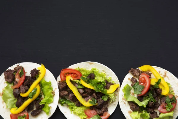 Tacos mexicanos con carne de res y verduras, cerveza y lima sobre fondo negro, vista superior. Copiar espacio. Puesta plana . —  Fotos de Stock