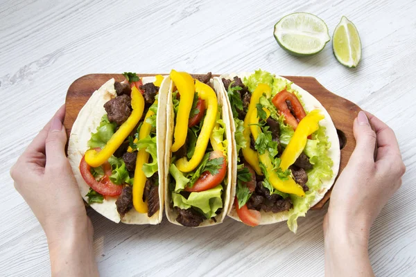 Frau hält ein Brett mit mexikanischen Tacos in der Hand, Draufsicht. — Stockfoto