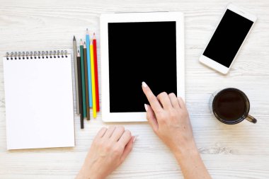 Tablet eller, smartphone, defter, renkli kalemler ve latte ile kadınsı çalışma alanı. Üstten Görünüm.