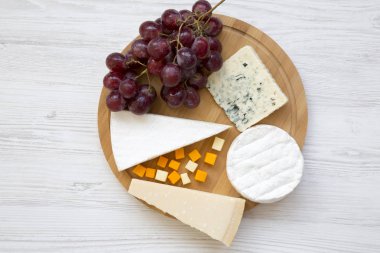 Peynir ile bir yuvarlak ahşap tahta üzerinde üzüm türleri tatmak. Yiyecek şarap, en iyi görünüm için. Düz yatıyordu. Yukarıdan.