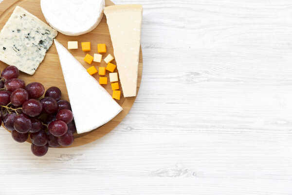 Tasting cheese with grapes on white wooden background. Food for wine, top view. Space for text. Flat lay. From above.