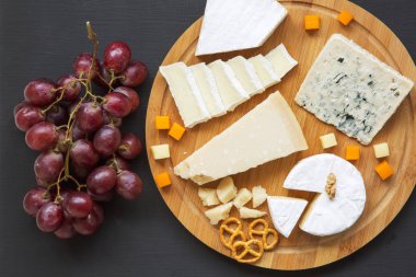 Yukarıdan üzüm, simit ve ceviz koyu arka plan üzerinde peynir tatma. Yiyecek şarap için. Üstten Görünüm. 