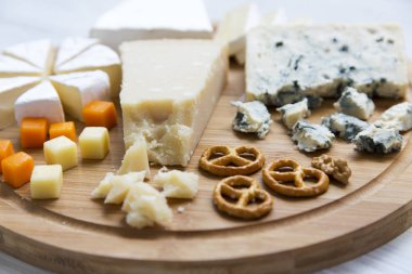 Lezzetli peynir: camembert, mavi peynir, brie, parmesan, mimolette ve edam simit ve üzerine ceviz ile yuvarlak ahşap tahta. Yiyecek şarap için. Portre.