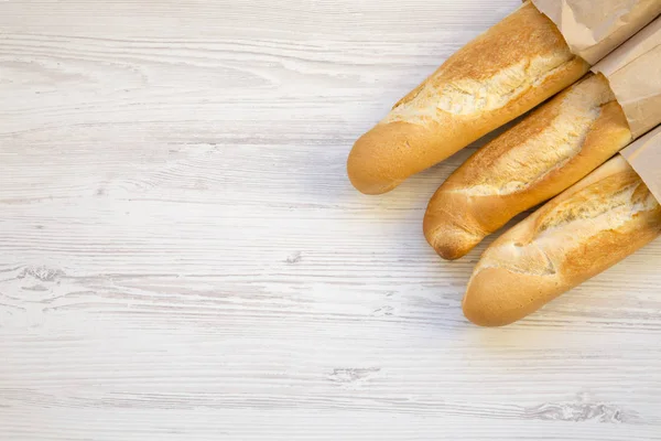 法国面包在纸袋上的白色木桌上 顶部视图 复制空间 — 图库照片