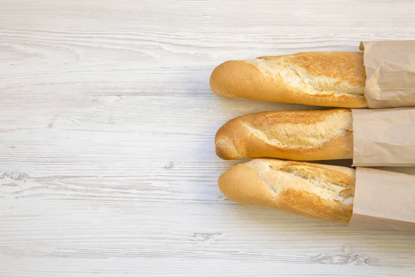 法国面包在纸袋上的白色木桌上 顶部视图 复制空间 — 图库照片