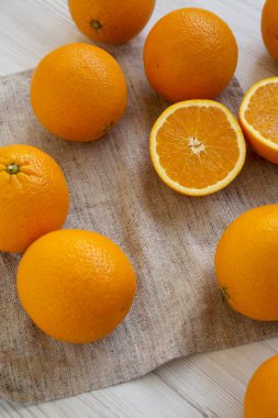 Beyaz ahşap bir masada taze taze organik portakallar.