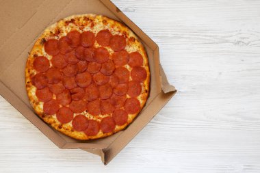 Beyaz ahşap bir yüzey üzerinde kutu içinde leziz Pepperoni pizzası.