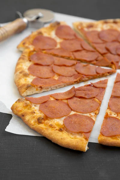 양피지에 있는 맛있는 페퍼로니 피자검은 표면, 측면 뷰 — 스톡 사진