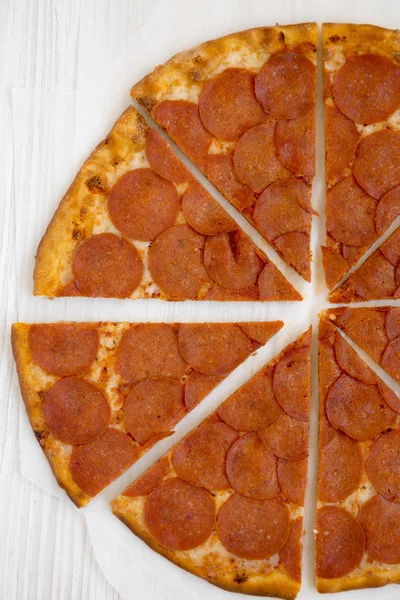 흰 나무 표면에 양피지에 놓인 맛있는 페퍼로니 피자 — 스톡 사진