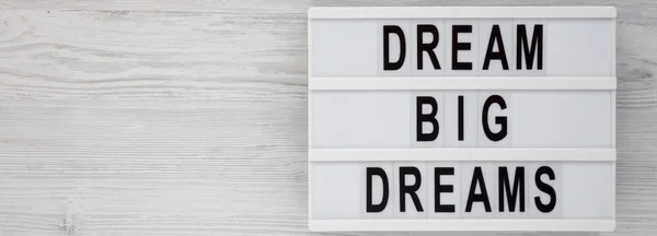 \'Dream big dreams\' words on a lightbox on a white wooden surface