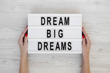 Kadın elleri ışık kutusunu 'Büyük hayaller kur' yazısıyla tutarlar.