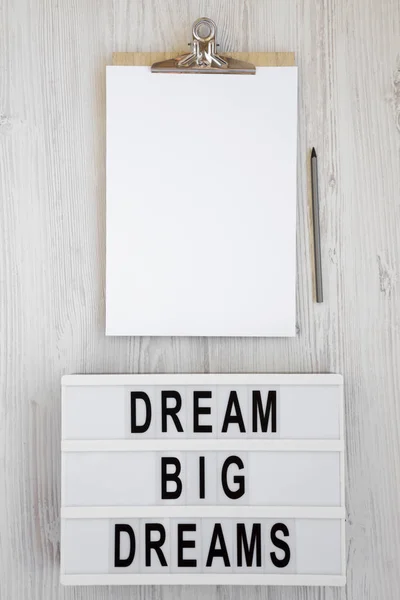 \'Dream big dreams\' words on a lightbox, clipboard with blank she