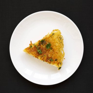 Siyah yüzey üzerinde beyaz bir tabakta ev yapımı spagetti omleti.,