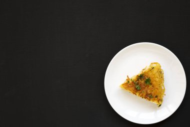 Siyah yüzey üzerinde beyaz bir tabakta ev yapımı spagetti omleti.,