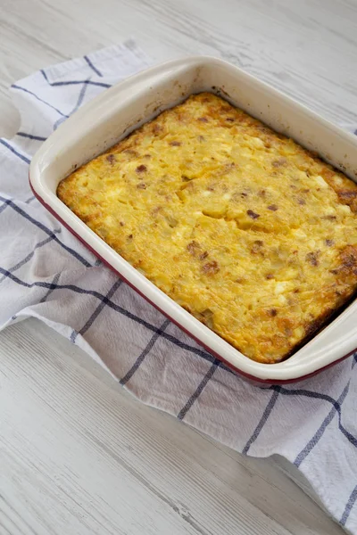 Homemade Cheesy Amish Breakfast Casserole on a white wooden surf