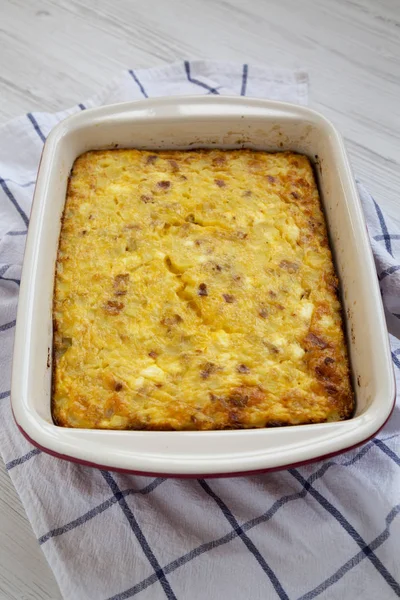 Home-baked Cheesy Amish Breakfast Casserole on a white wooden ba