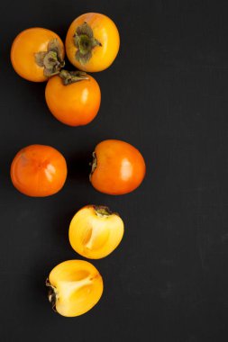 Siyah yüzeyde ham olgun portakal hurmaları, üst manzara. Düz yatıyordu,