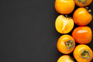 Siyah yüzeyde ham olgun portakal hurmaları, üst manzara. Düz yatıyordu,