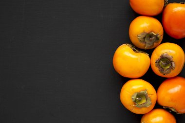 Siyah arka planda ham olgun portakal hurmaları, üst manzara. Düz!