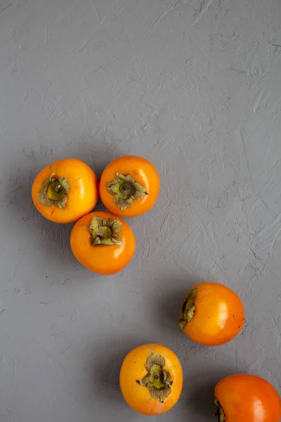 Raw Ripe Orange Persimmons on gray background, top view. Flat la — Stock Photo, Image