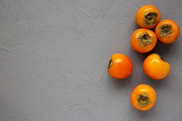 Raw maduro laranja caqui na superfície cinza, vista superior. Depósito plano , — Fotografia de Stock