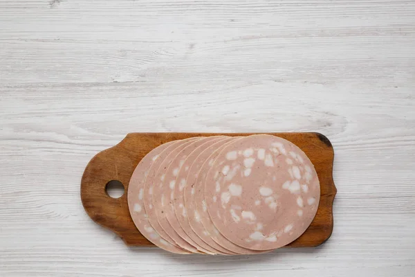 Sliced Mortadella Bologna Meat on a rustic wooden board over whi