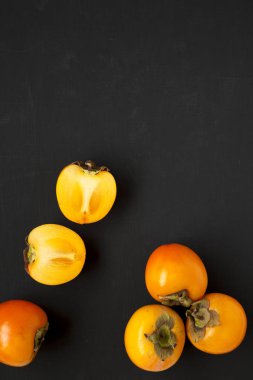 Siyah yüzeyde ham olgun portakal hurmaları, üst manzara. Düz yatıyordu,