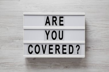 Korunuyor musun? Beyaz ahşap bir torba üzerinde modern bir tahtada kelimeler