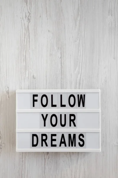 'Suivez vos rêves 'mots sur une lightbox sur un fond en bois blanc — Photo