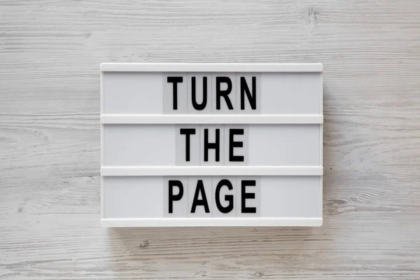 \'Turn the page\' words on a modern board on a white wooden backgr